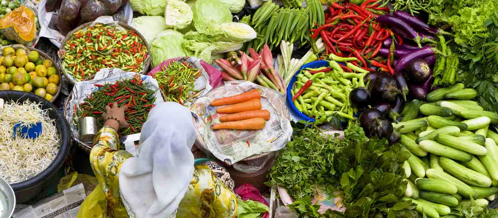 Mujer vendiendo vegetales en un mercado en Malasia