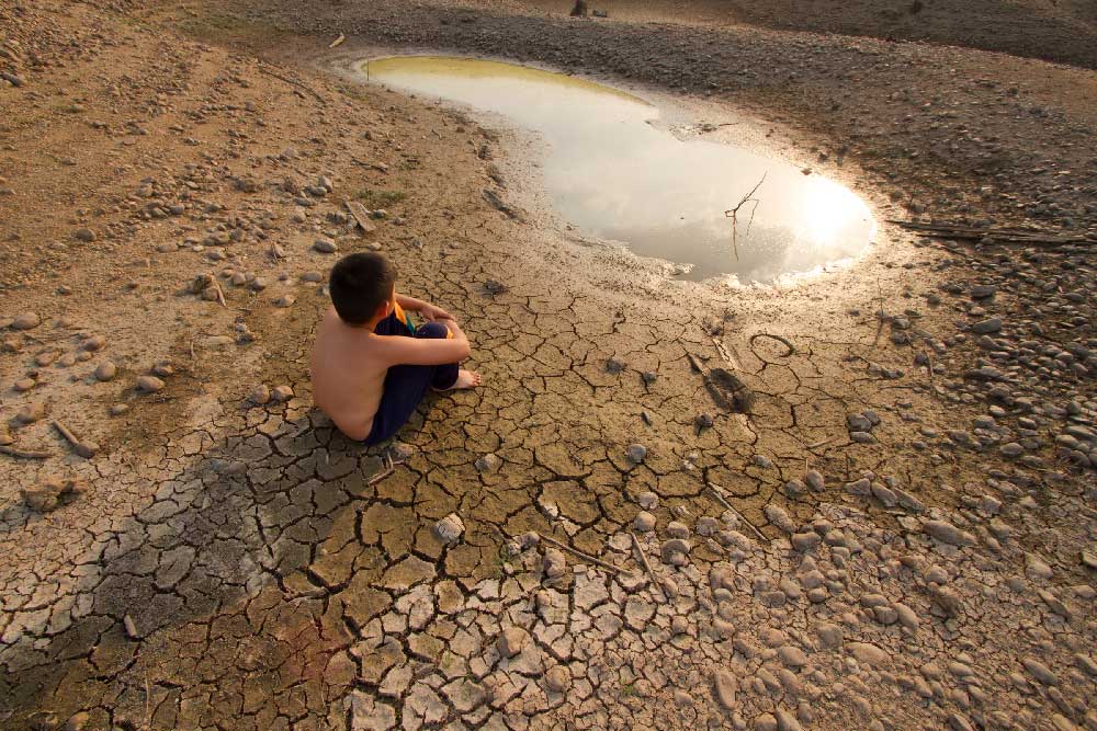 Un niño está sentado junto a un lago seco (Informe Planeta Vivo)